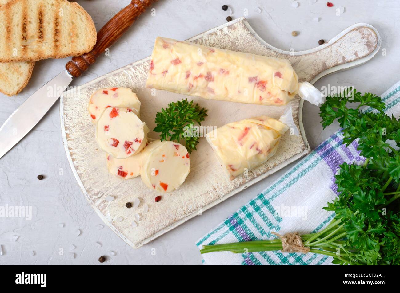 Porzioni di burro di erbe con pezzi di pepe dolce per panini e bistecche tagliate su un pannello di legno. Piatti italiani fatti in casa. La vista dall'alto Foto Stock