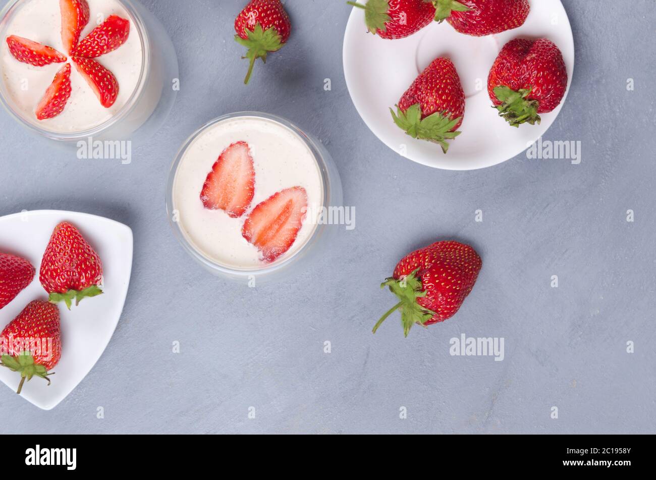 Dessert di fragole in un vaso di vetro con fragole fresche su un tavolo grigio Foto Stock