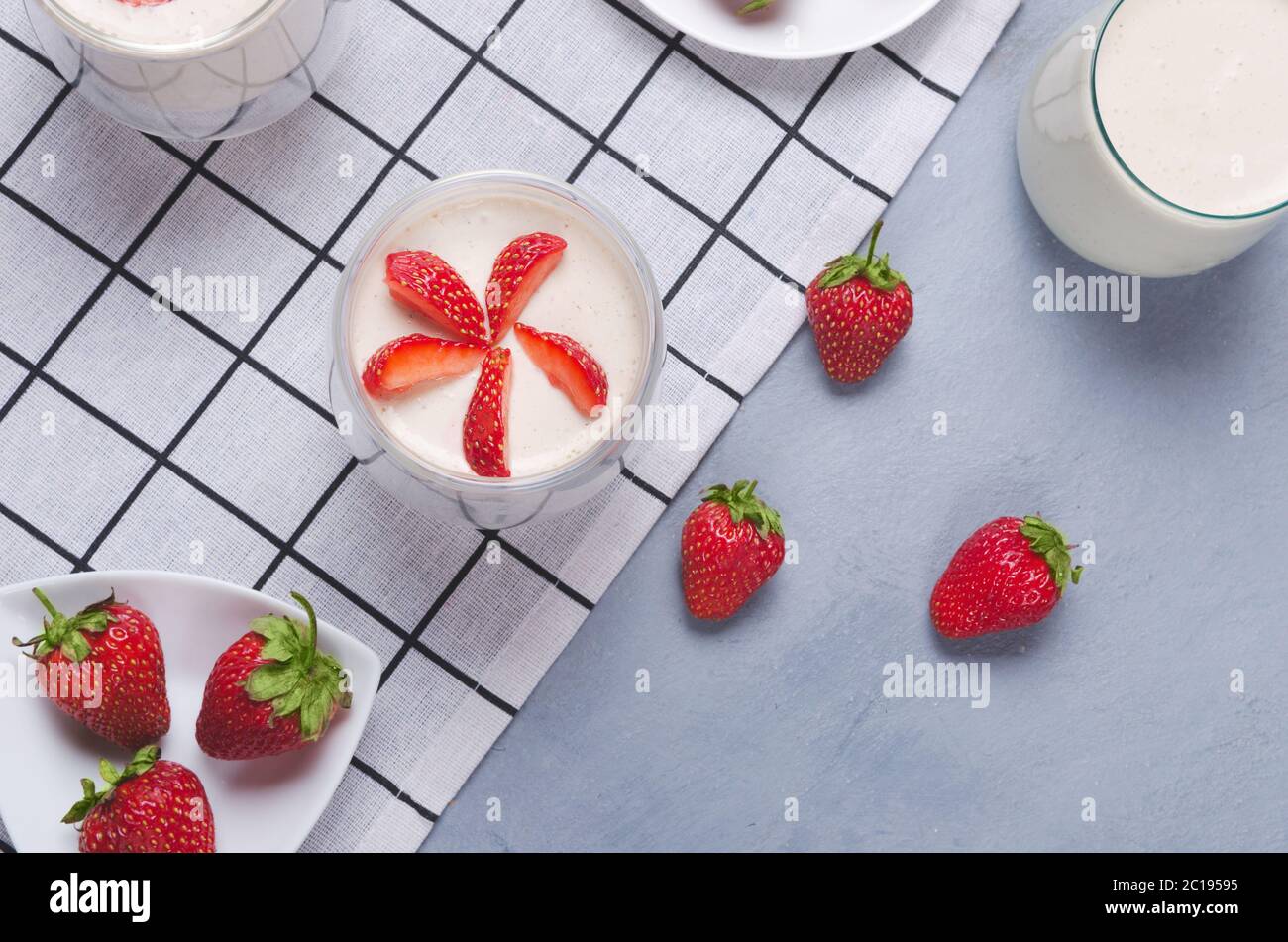 Dessert di fragole in un vaso di vetro con fragole fresche su un tavolo grigio con tovagliolo di lino Foto Stock