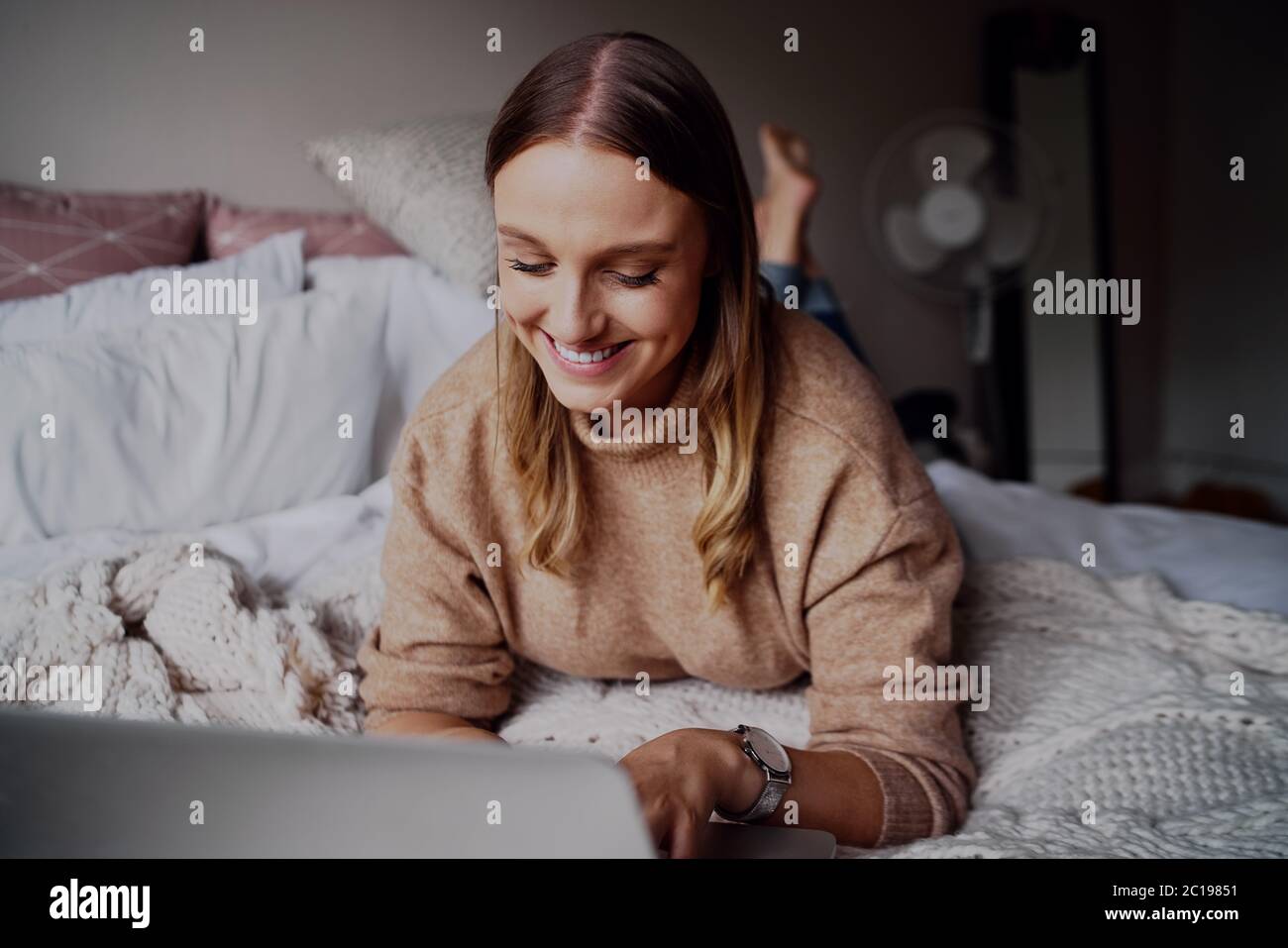 Ritratto di giovane donna d'affari allegra che lavora sul suo laptop nella sua camera da letto a casa - studente che impara online corsi a. Foto Stock