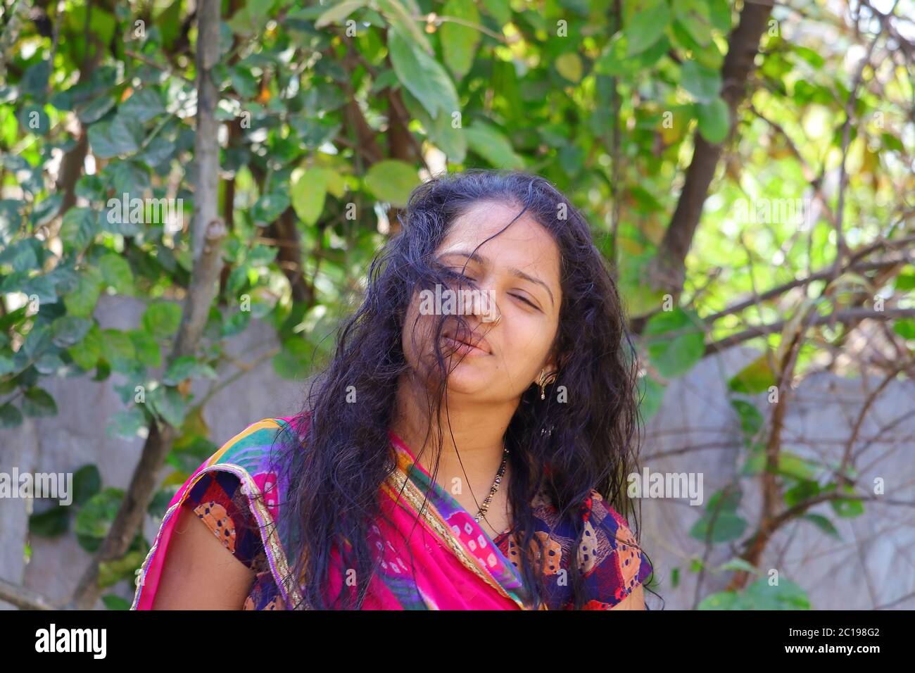 Vista frontale di una giovane ragazza indiana che si trova nel giardino di casa Foto Stock