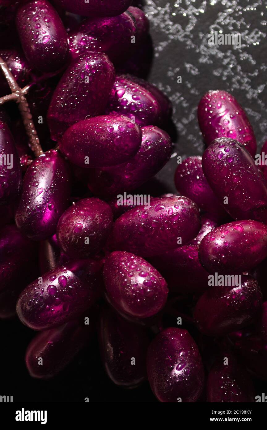 Uva finta con gocce d'acqua su sfondo scuro Foto stock - Alamy