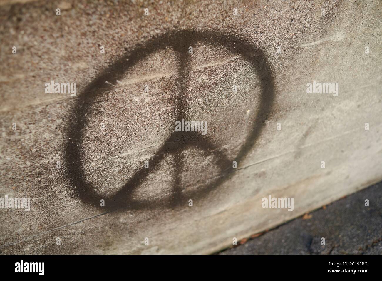 Simbolo della campagna per il disarmo nucleare, noto anche come simbolo della pace graffiti su un muro di cemento Foto Stock