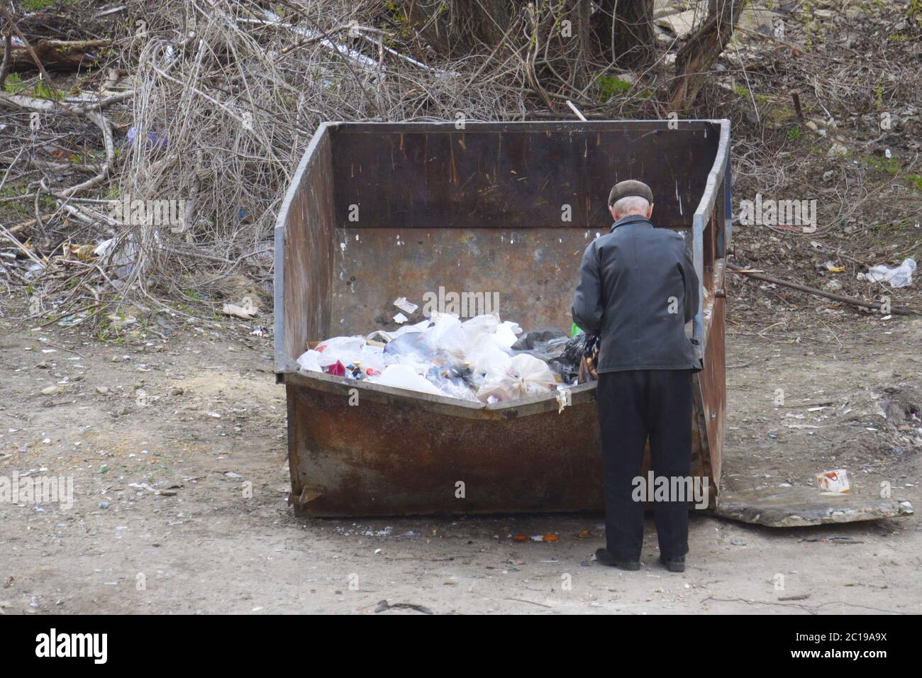 Un uomo senza casa cerca cibo in un cestino Foto stock - Alamy