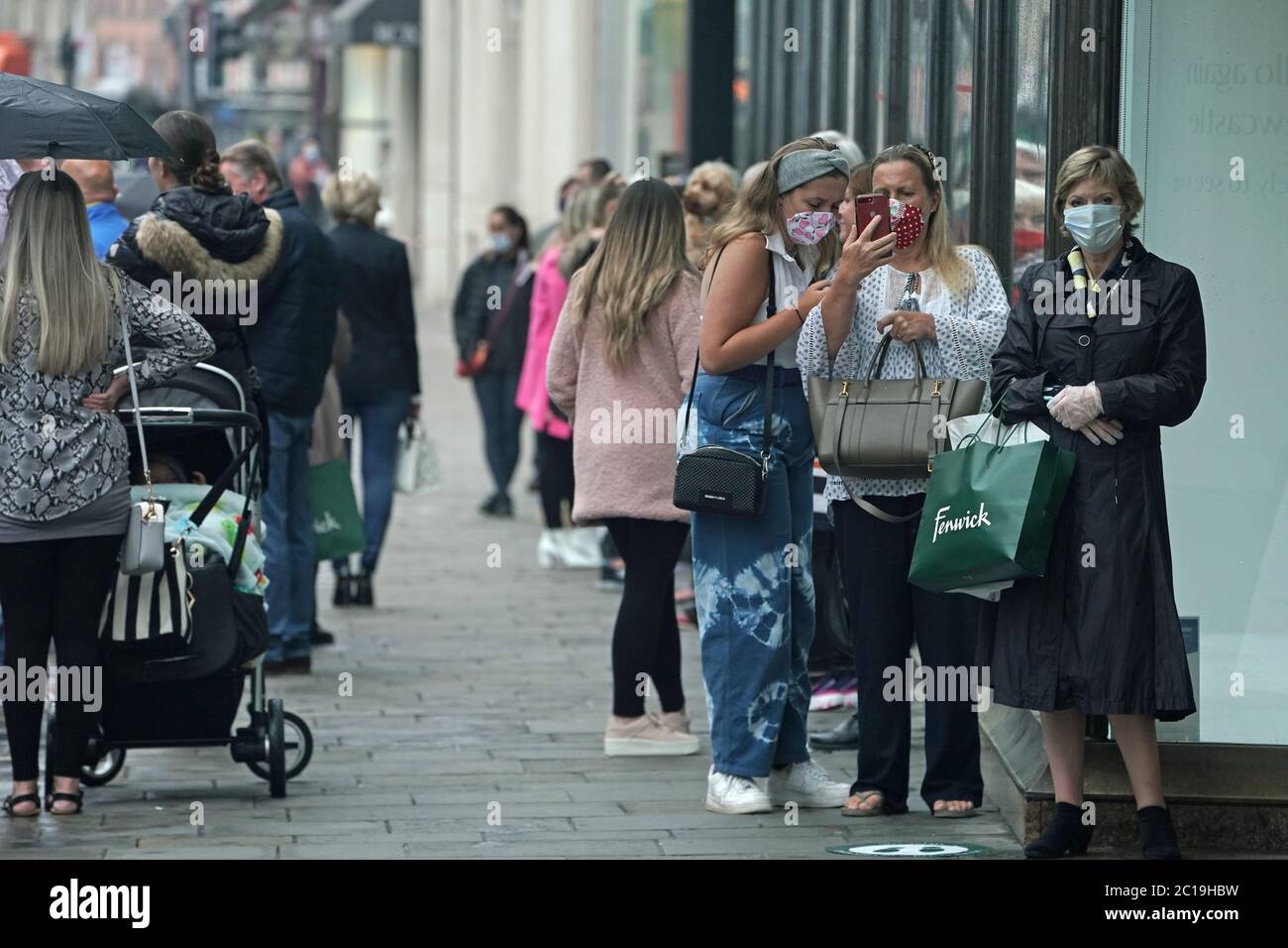 Gli acquirenti che indossano maschere facciali in coda per entrare nel negozio Fenwick di Northumberland Street, Newcastle, mentre i negozi non essenziali in Inghilterra aprono le porte ai clienti per la prima volta da quando le restrizioni di blocco di coronavirus sono state imposte a marzo. Foto Stock