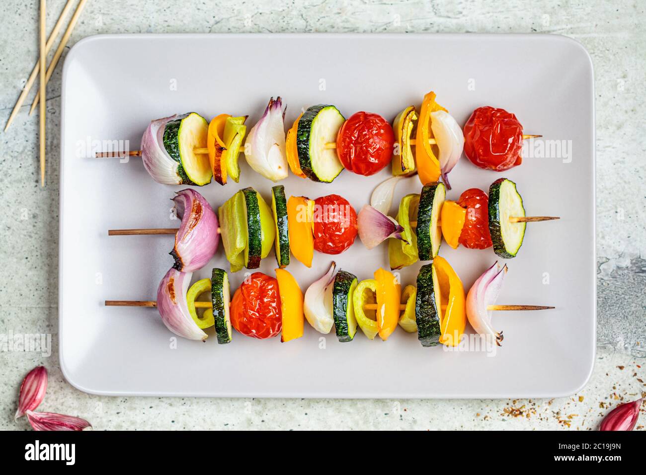 Spiedini grigliati di verdure su una piastra rettangolare grigia. Concetto di cibo vegano. Foto Stock