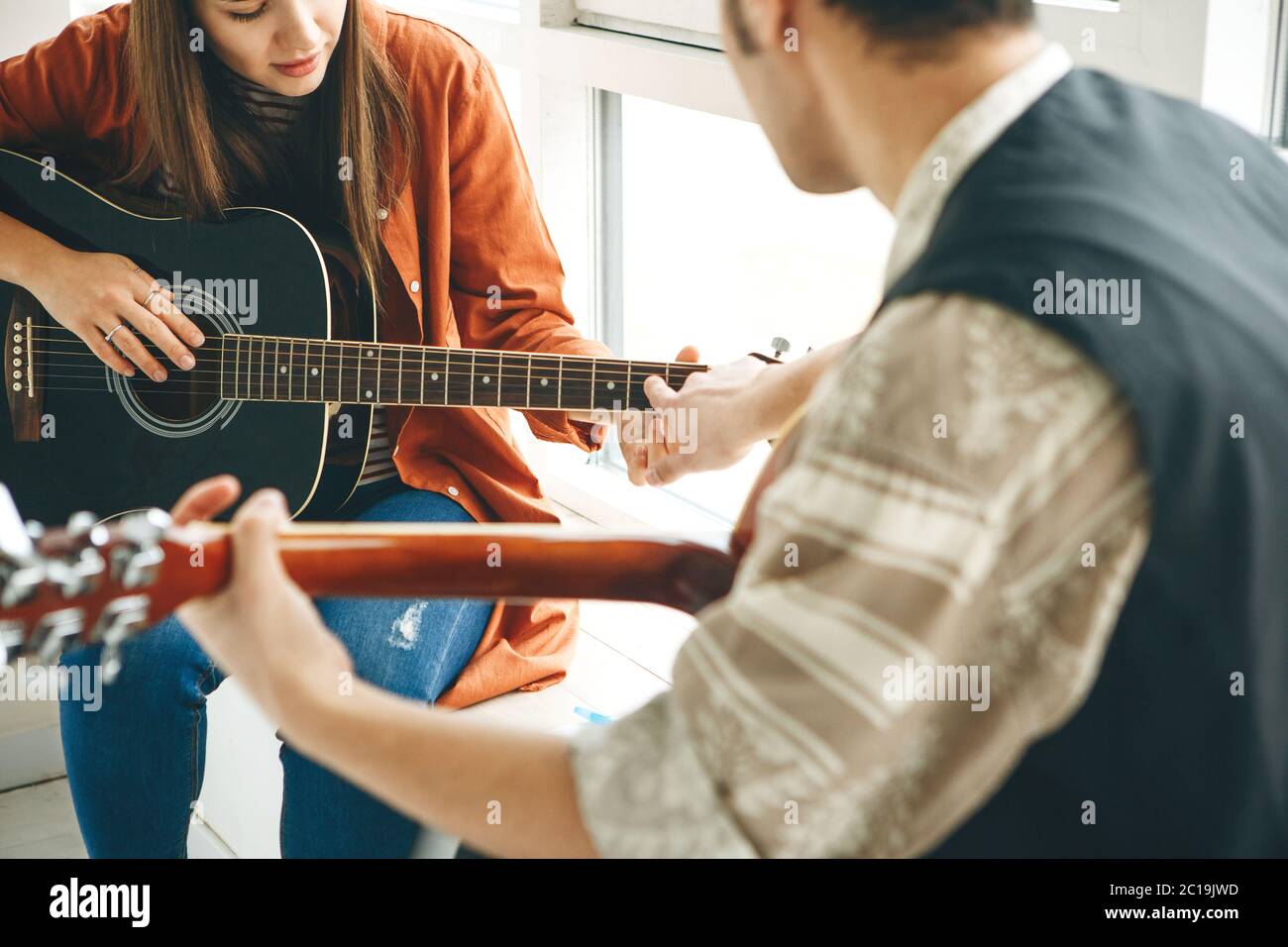 Imparare a suonare la chitarra. L'insegnante spiega allo studente le basi per suonare la chitarra. Lezioni individuali di scuola domestica o extracurricolare. Foto Stock