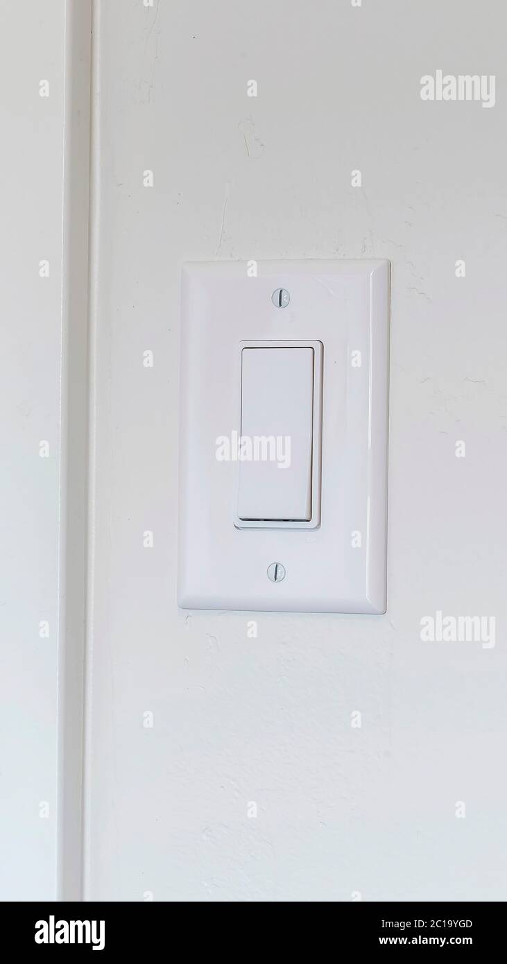 Interruttore di illuminazione elettrica verticale per interni della casa montato su sfondo bianco Foto Stock
