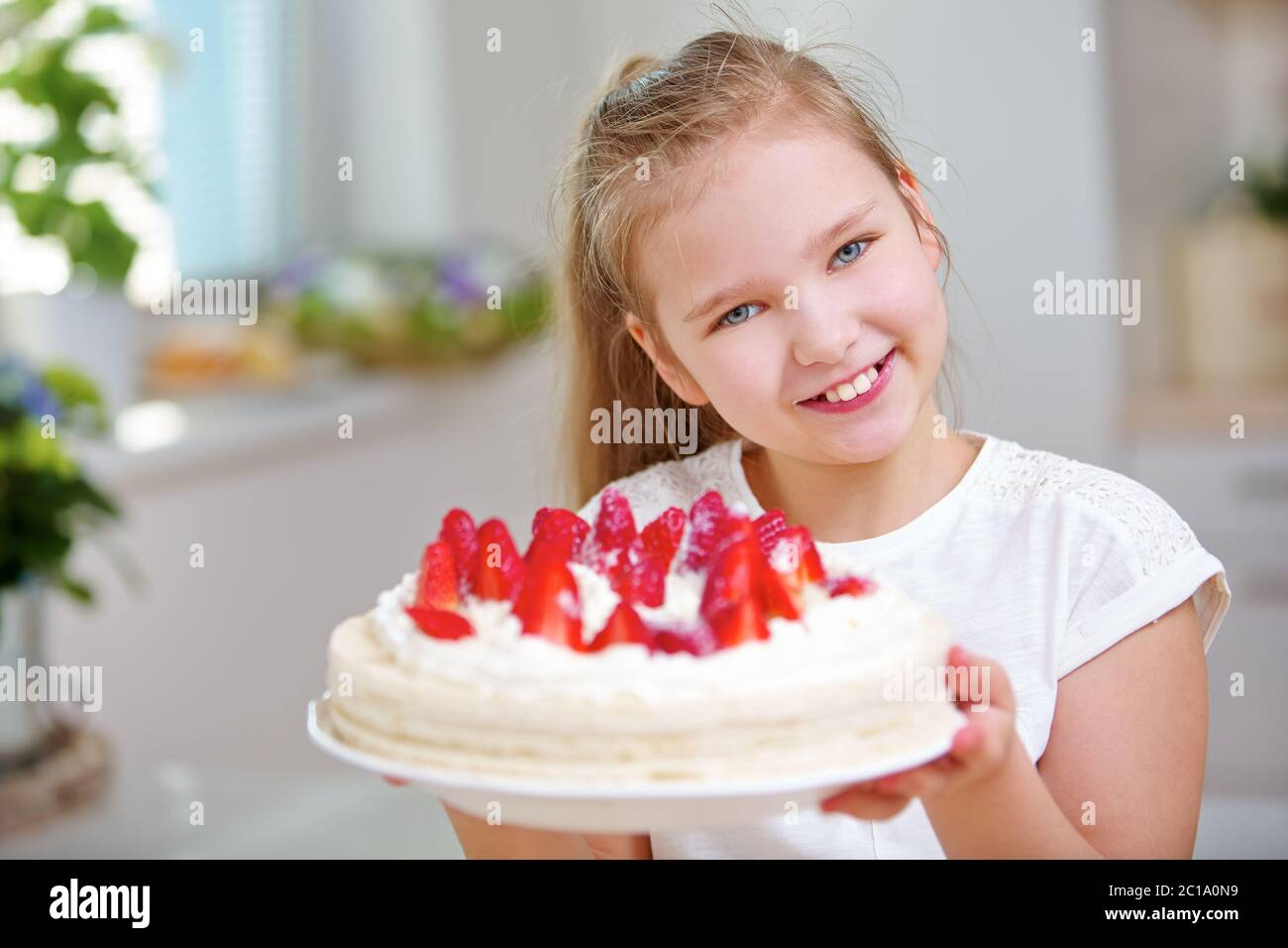 Happy child tiene una torta di fragole con fragole fresche in entrambe le mani Foto Stock