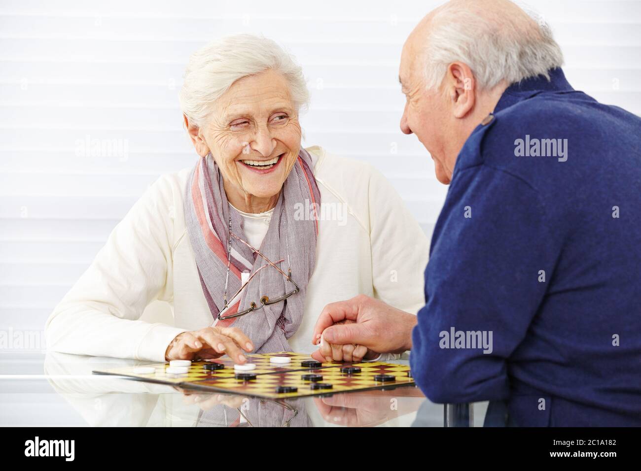 Felice coppia senior che gioca la signora del gioco da tavolo nella casa di riposo Foto Stock
