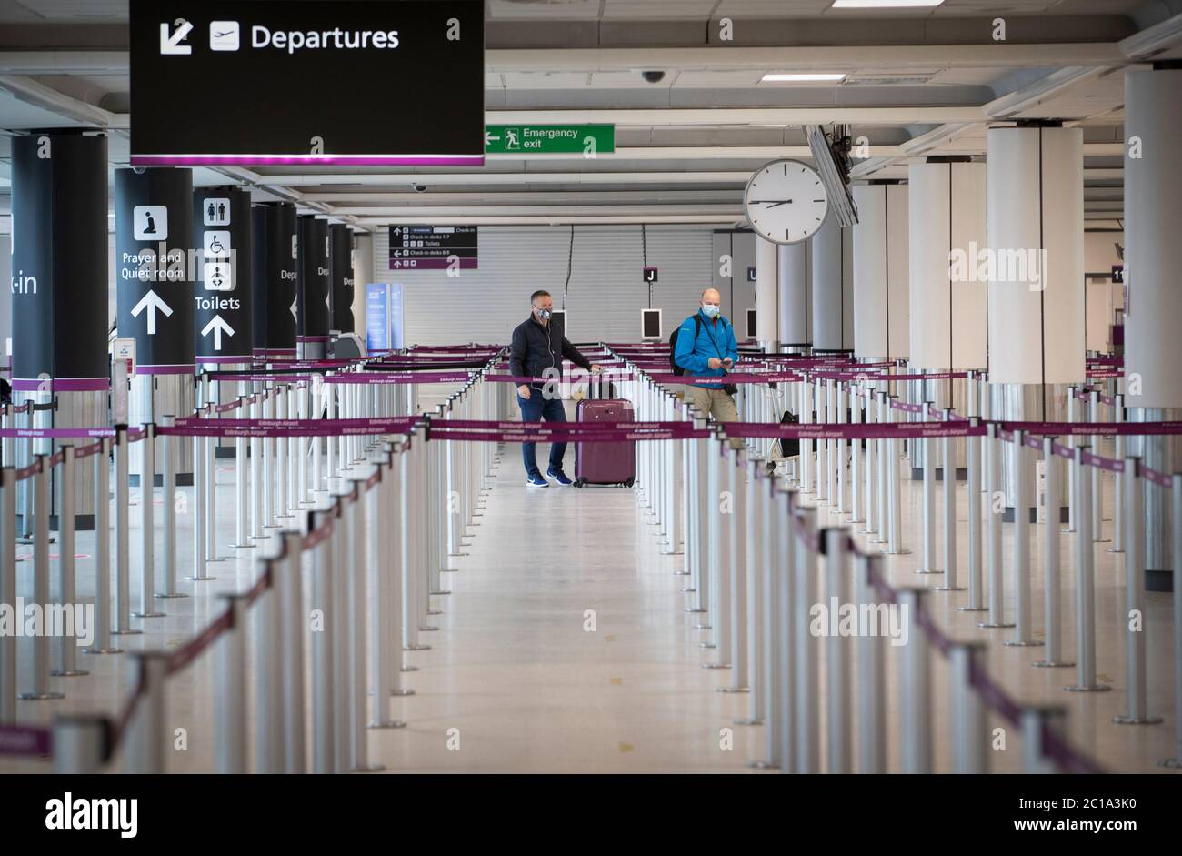 I passeggeri, indossando una maschera protettiva per il viso, attendono presso l'area di check-in dell'aeroporto di Edimburgo. Foto Stock