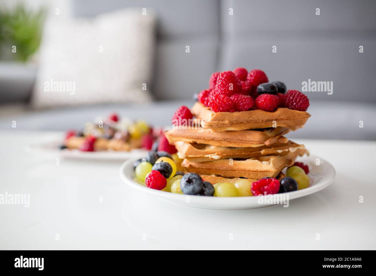 Dolce ragazzo di compleanno del bambino, mangiando waffle belgi con lamponi, mirtilli, cocnoci e cioccolato a casa Foto Stock