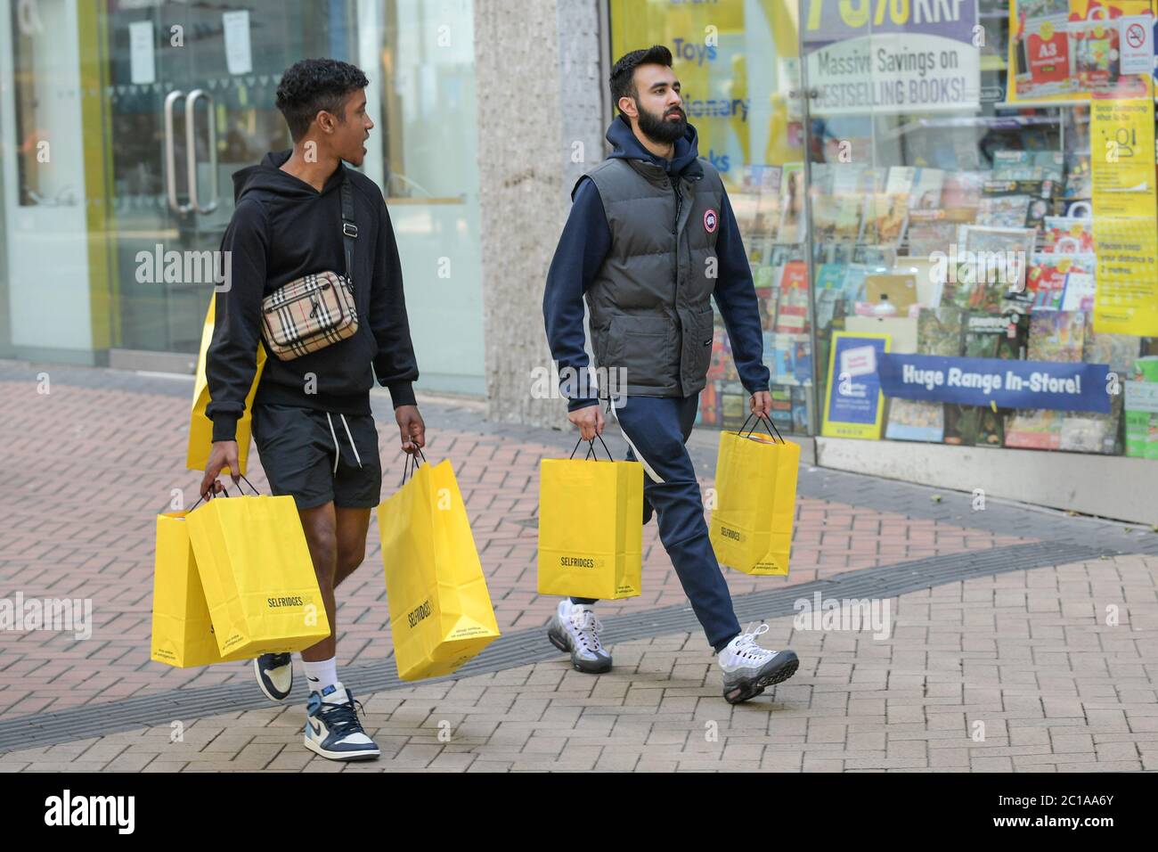 Birmingham, West Midlands, 15 giugno 2020. Due uomini trasportano sei sacchetti di shopping da Selfridges a Birmingham, mentre migliaia di acquirenti sono usciti per acquistare articoli che hanno perso da quando i negozi sono stati chiusi durante il periodo di blocco COVID-19. Molti di loro erano in possesso di pacchetti di borse dopo un giro di shopping. Due uomini sono stati visti camminare lungo la New Street di Birmingham con sei borse Selfridges. Credito: Interrompi stampa Media/Alamy Live News Foto Stock