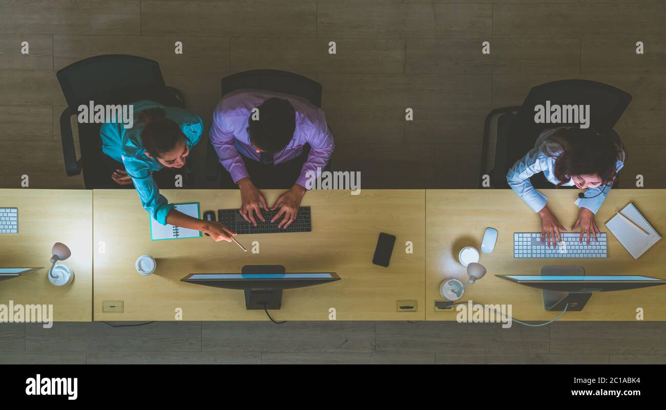 Vista dall'alto dell'Asian Male Customer Care Service che lavora duro a tarda notte in ufficio, reparto call center, lavoratore e straordinario, lavoro di squadra con coll Foto Stock Vista dall'alto dell'Asian Male Customer Care Service che lavora duro a tarda notte in ufficio, reparto call center, lavoratore e straordinario, lavoro di squadra con coll Foto Stock