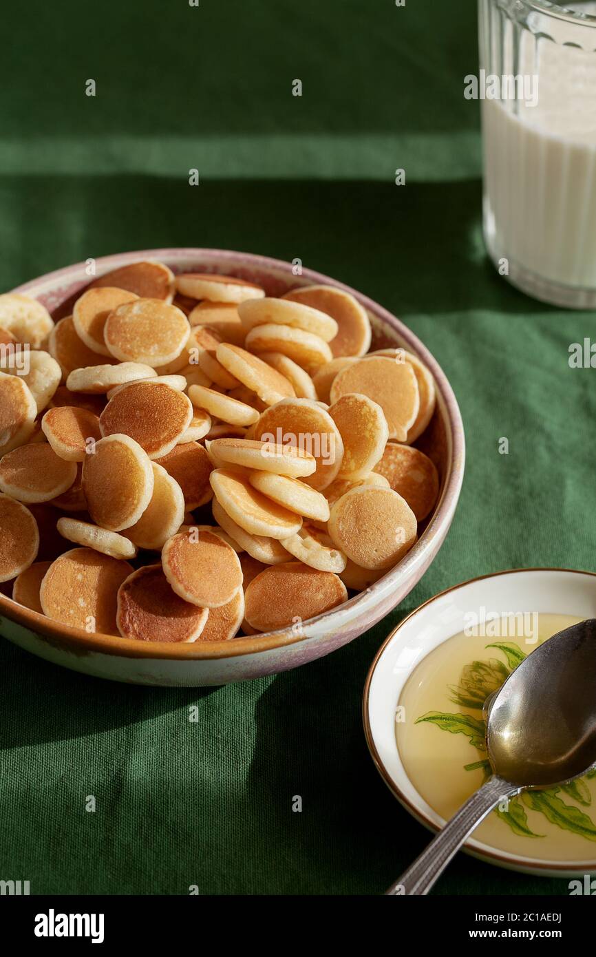Ciotola con minuscolo porridge di cereali pancake su sfondo tessile verde. Gustosi piatti per la colazione alla moda Foto Stock