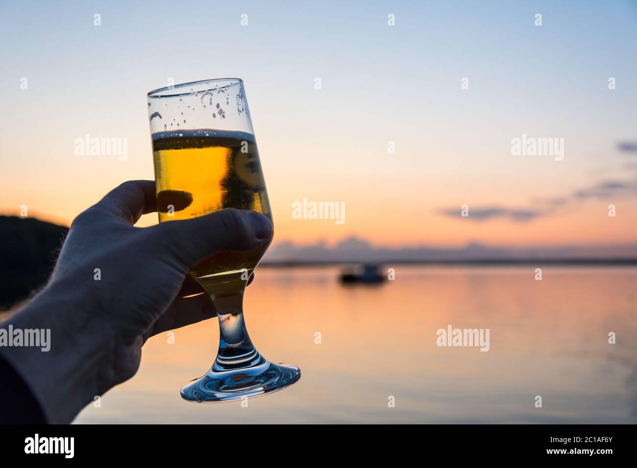 Una birra fresca e fredda in riva al mare durante un bellissimo tramonto Foto Stock