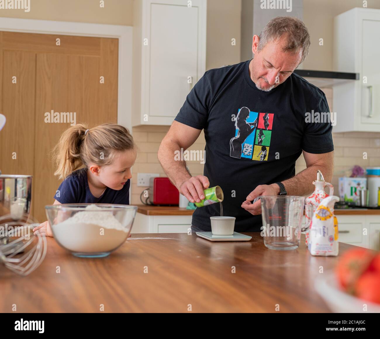 Daddy e figlia che fanno pasta fresca per pizza in cucina mixer. Cottura di corona Lockdown. Fare la pizza con Daddy durante il blocco. Foto Stock