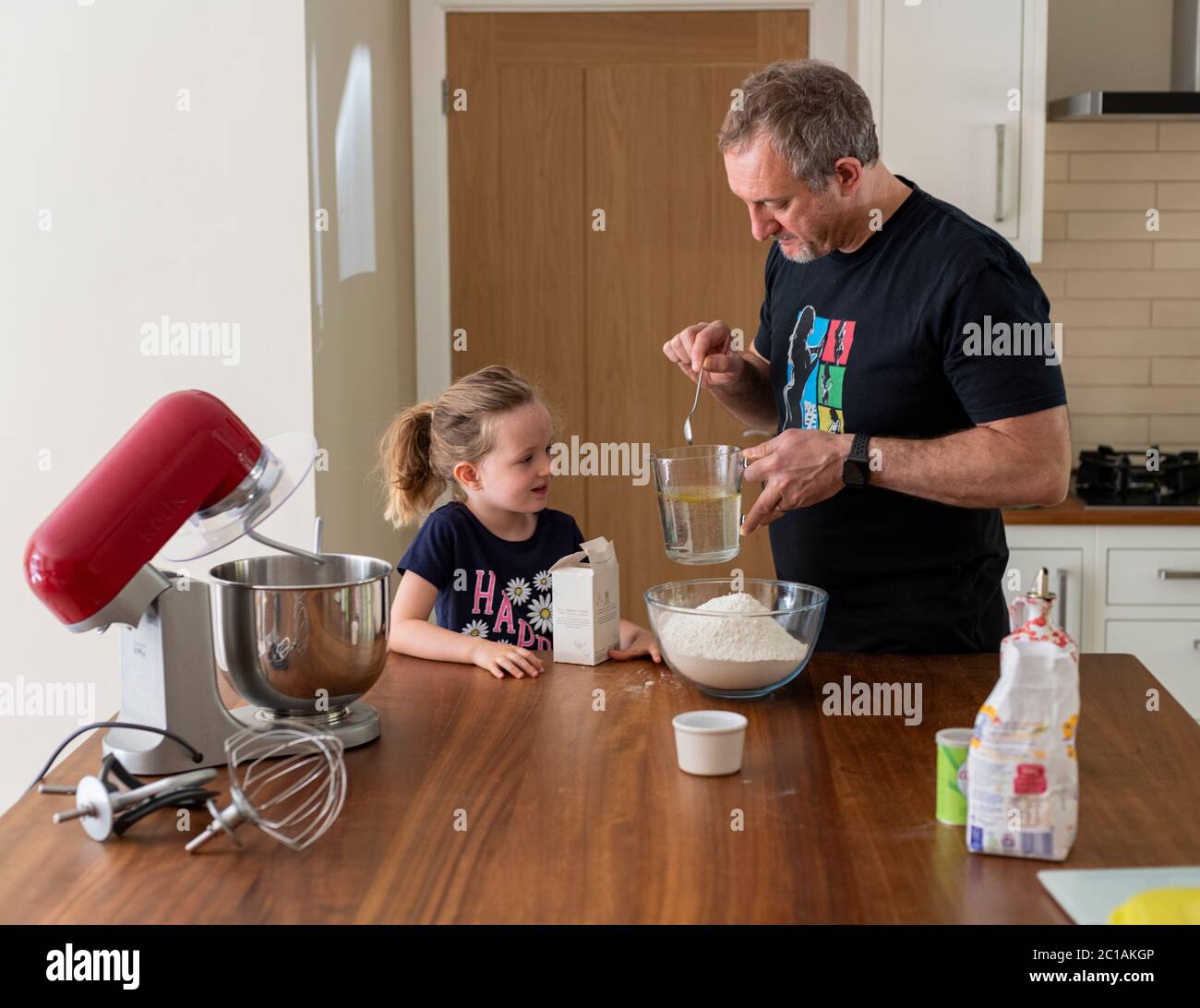 Daddy e figlia che fanno pasta fresca per pizza in cucina mixer. Cottura di corona Lockdown. Fare la pizza con Daddy durante il blocco. Foto Stock