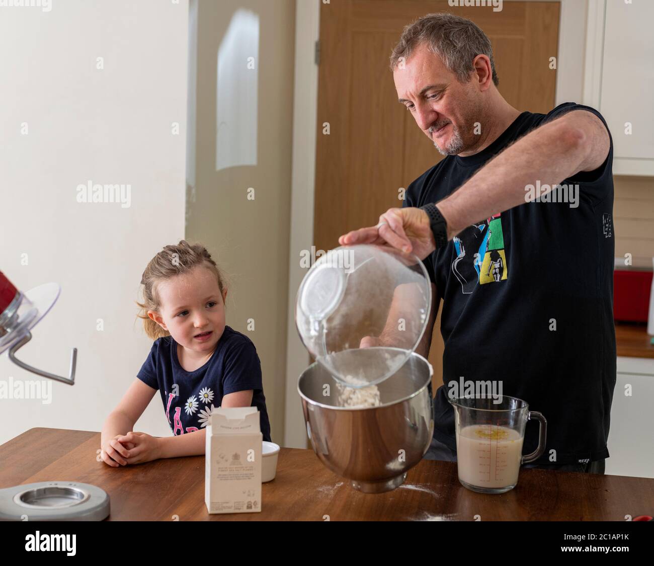 Daddy e figlia che fanno pasta fresca per pizza in cucina mixer. Cottura di corona Lockdown. Fare la pizza con Daddy durante il blocco. Foto Stock