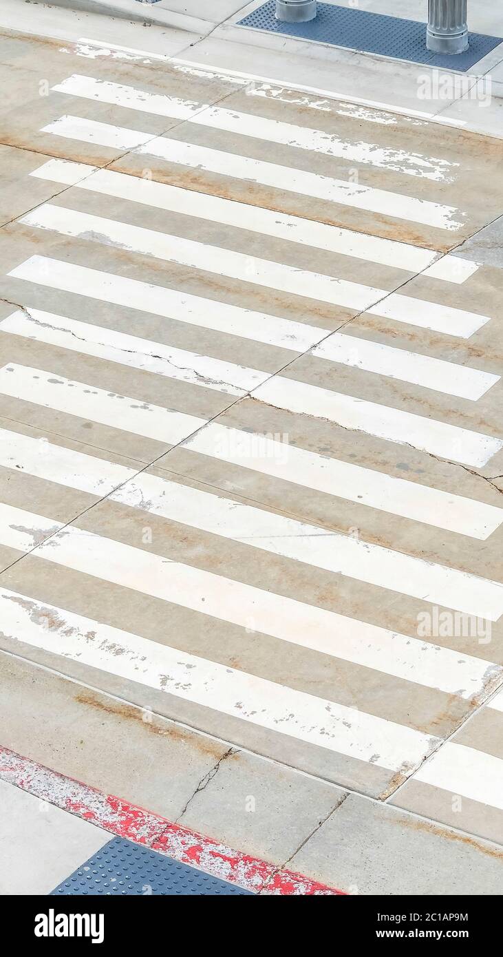 Raccolto verticale pedone che attraversa linee bianche dipinte sulla strada di fronte all'edificio Foto Stock