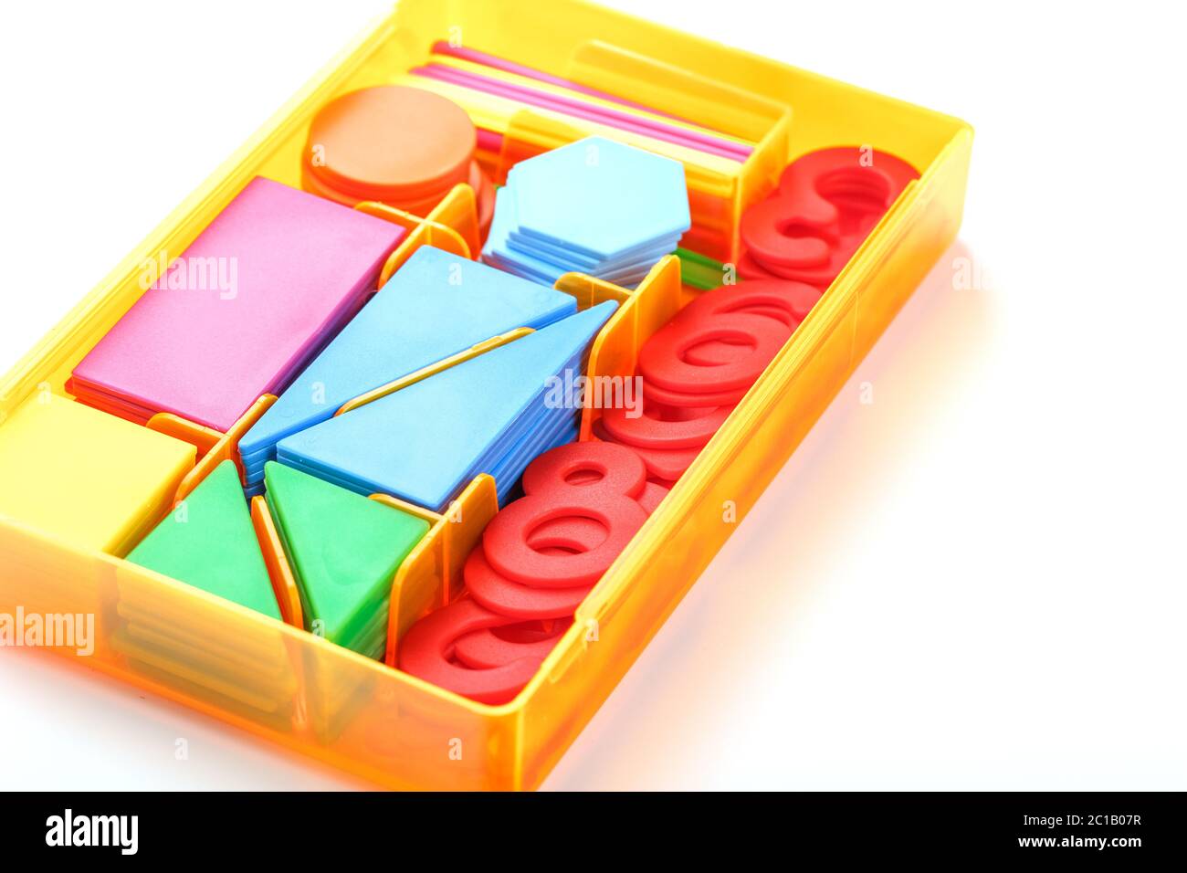 Una scatola con figure e numeri di plastica colorati su sfondo bianco. Giochi educativi per bambini. Foto Stock