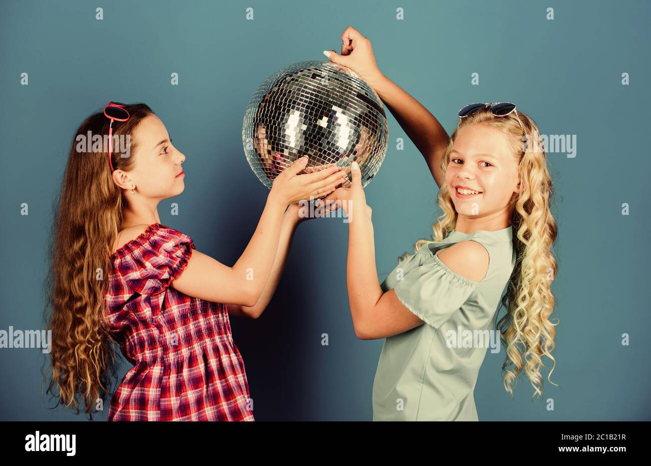 Musica retrò. Gli specchi riflettenti discoteca luci di atmosfera. Holiday celebrazione. Concetto di intrattenimento. Sorelle amici con palla da discoteca. Iniziare a parte. Allegro kids tenere palla da discoteca. Discoteca danze. Foto Stock