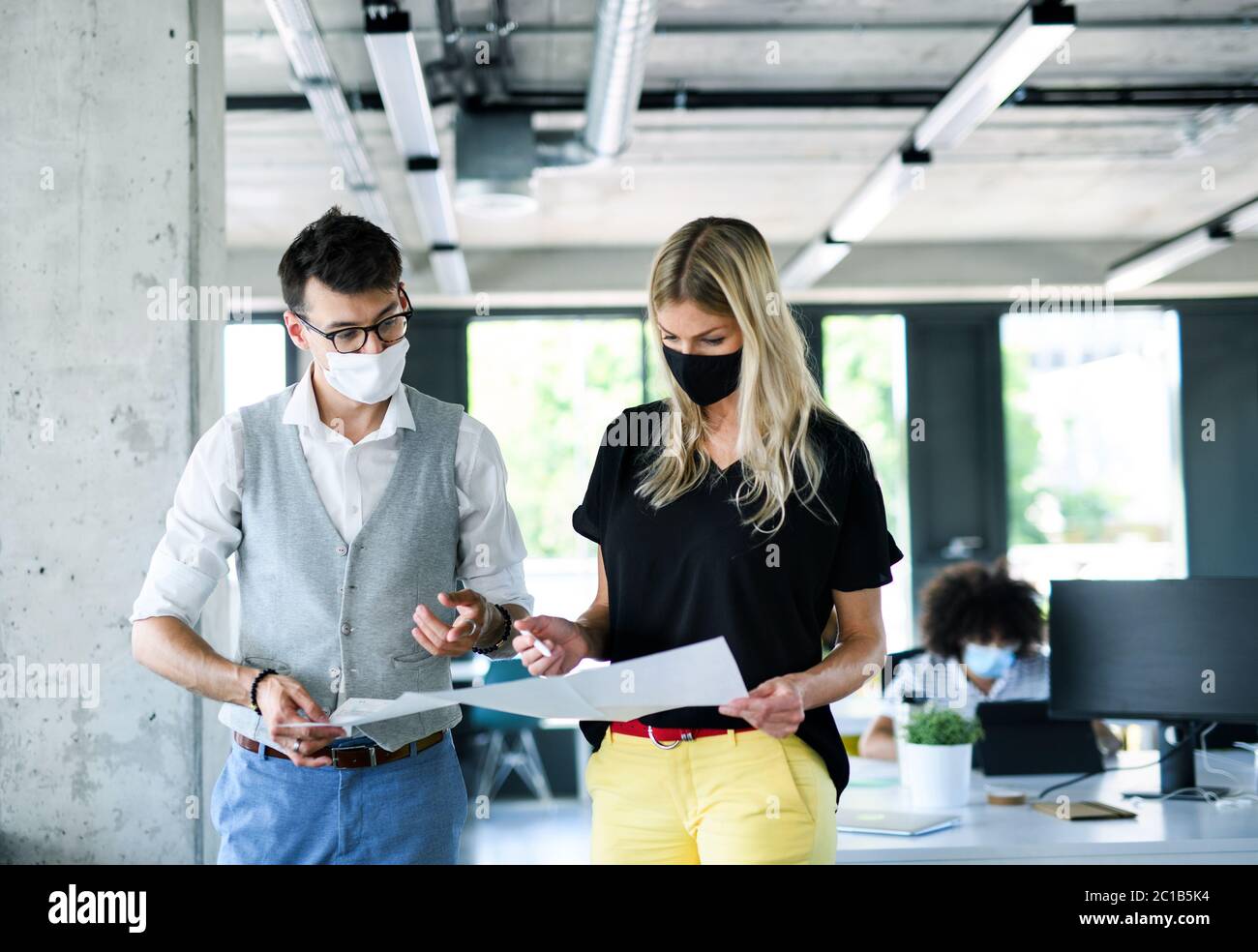 I giovani con maschere facciali tornano al lavoro dopo il blocco. Foto Stock