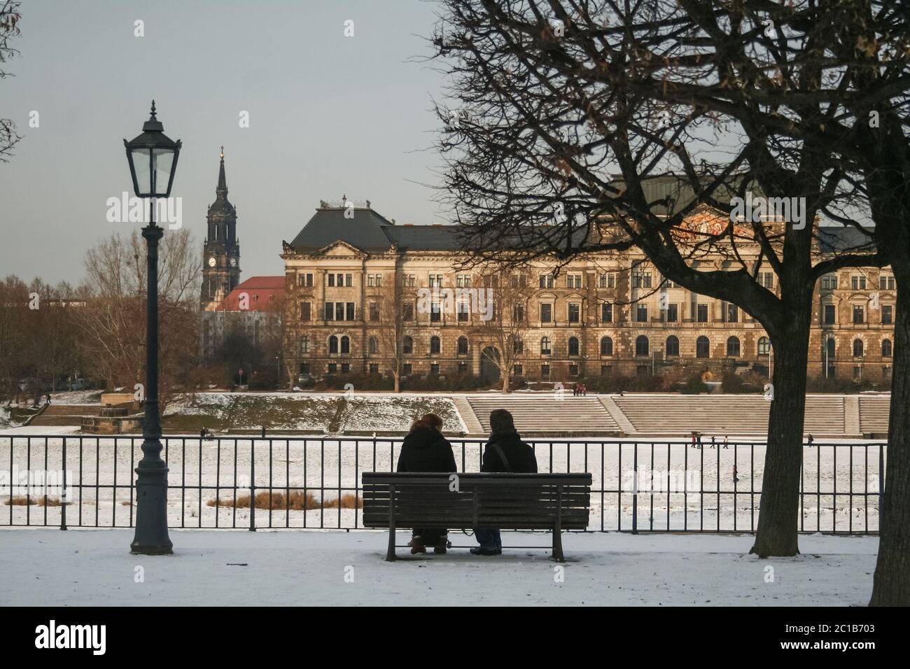 DRESDA, GERMANIA - 8 DICEMBRE 2012: A persone, amanti, seduti su Terrassenufer, la riva del fiume Elba della città, in inverno, durante un freddo tramonto, wi Foto Stock
