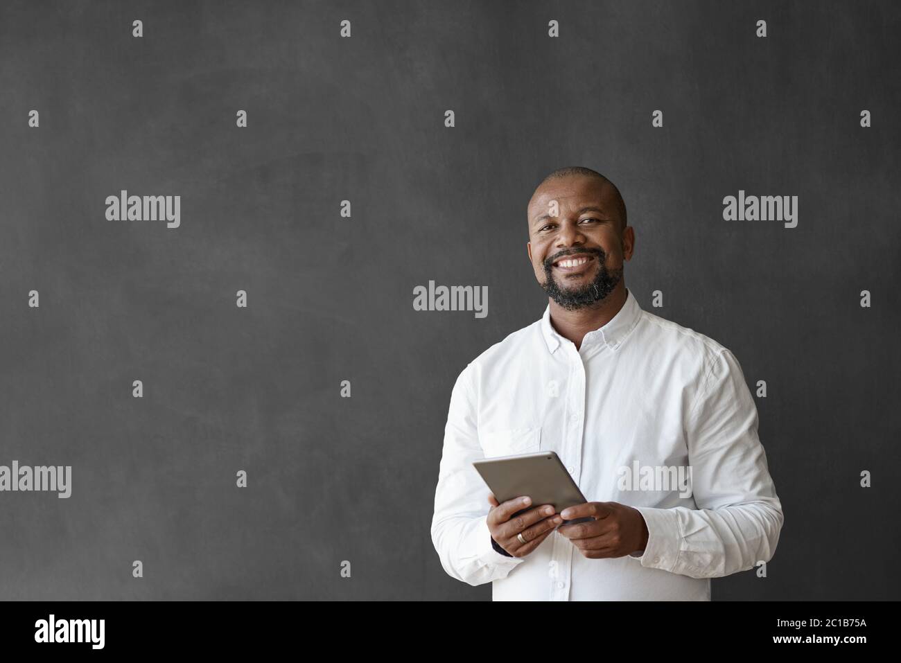 Sorridente uomo d'affari afro-americano utilizzando un tablet da una lavagna Foto Stock