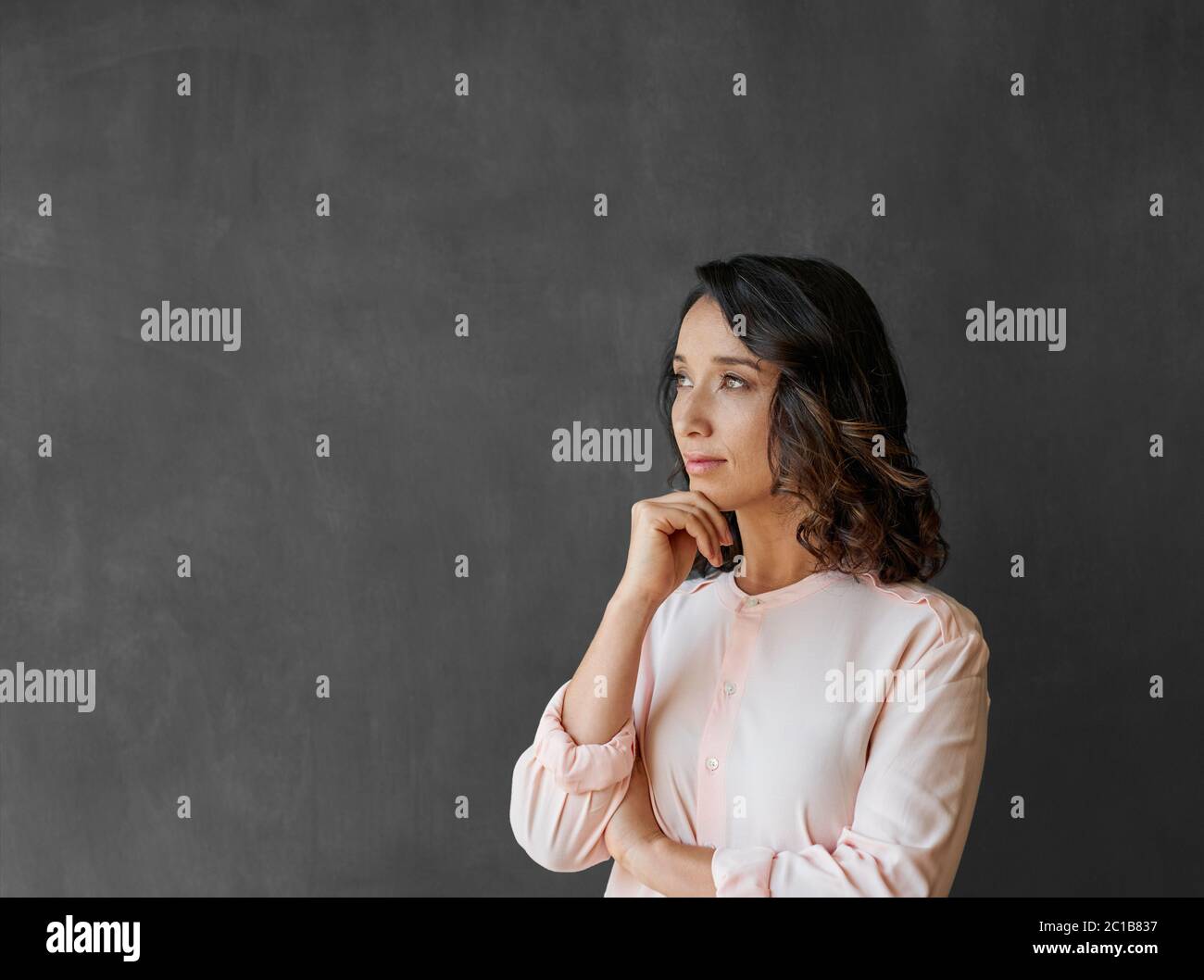 Giovane donna d'affari asiatica in piedi da una lavagna profonda nel pensiero Foto Stock