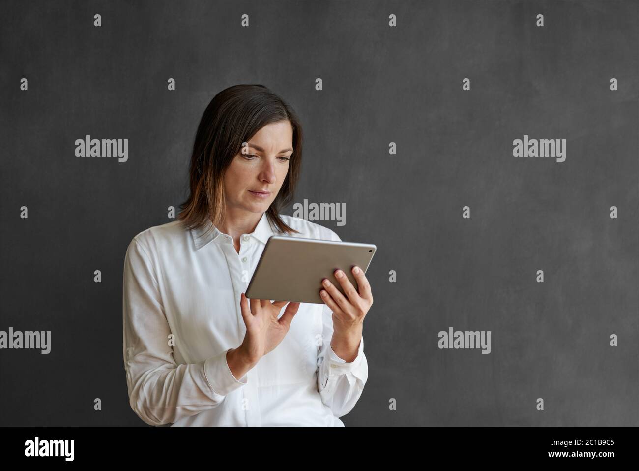 Donna d'affari che usa un tablet davanti a una lavagna vuota Foto Stock