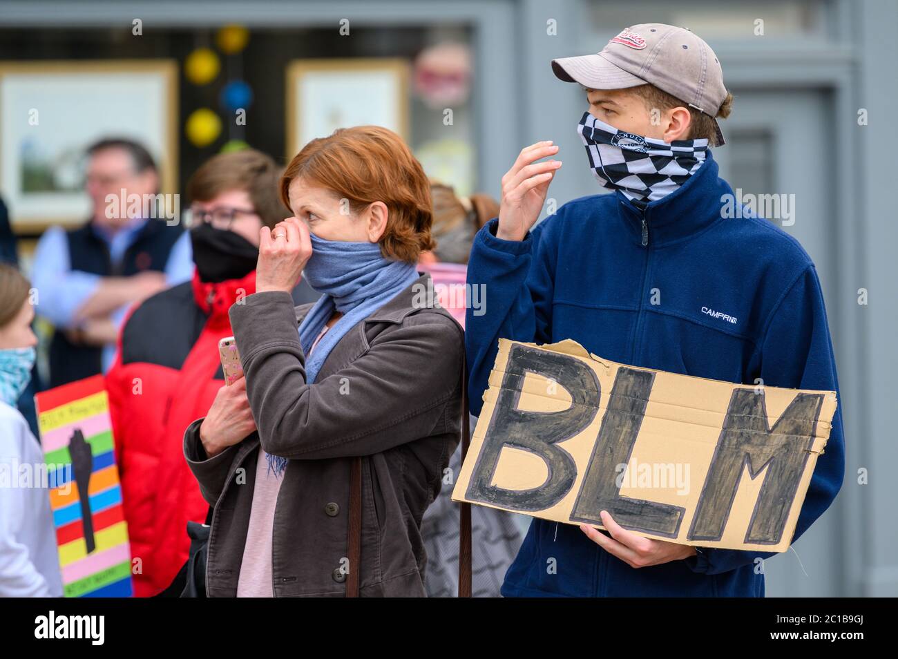 Richmond, North Yorkshire, UK - 14 giugno 2020: Due manifestanti BLM regolano i rivestimenti protettivi mentre tengono un cartello fatto in casa a Black Live Foto Stock