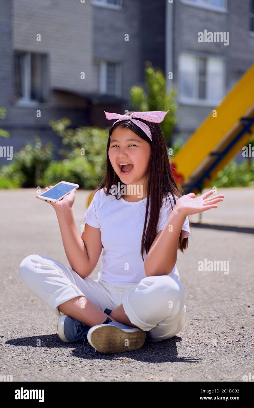 Bella bambina asiatica con il telefono sulla strada è sorpreso Foto Stock