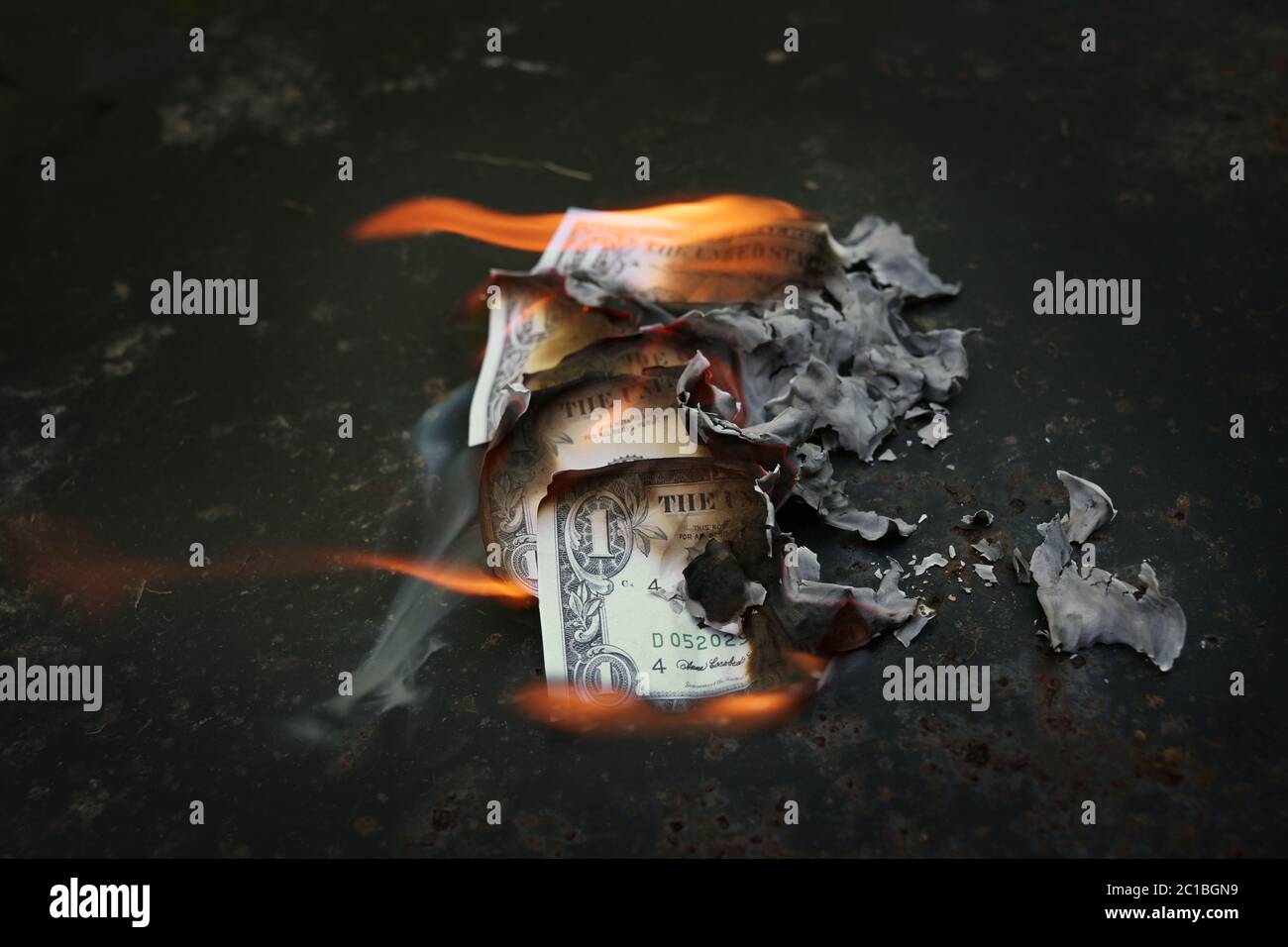 Denaro bruciato, bollette in dollari sul fuoco, concetto finanziario per la crisi economica, crollo del mercato azionario, riduzione dei salari o inflazione, sfondo oscuro con copia Foto Stock