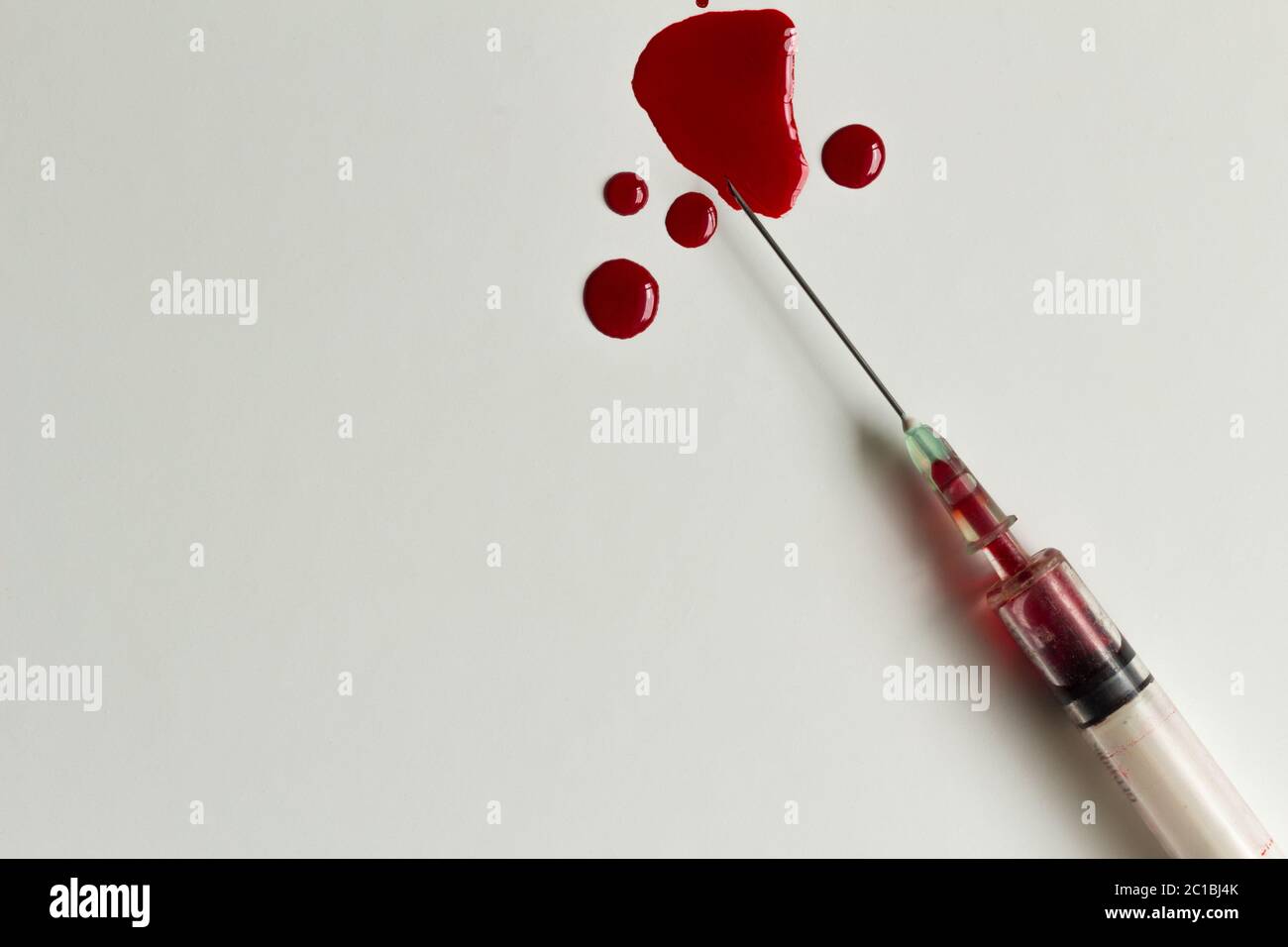 Siringa con il sangue e il sangue schizza closeup e isolato su sfondo bianco Foto Stock