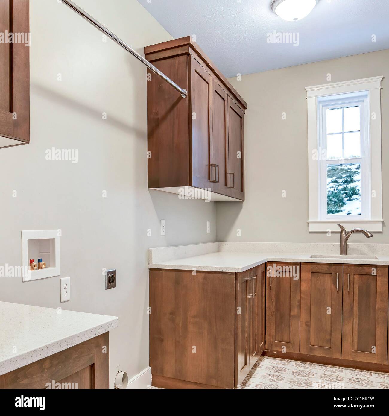 Cornice quadrata interno cucina con mobili in legno marrone banconi bianchi  lavello e finestra Foto stock - Alamy