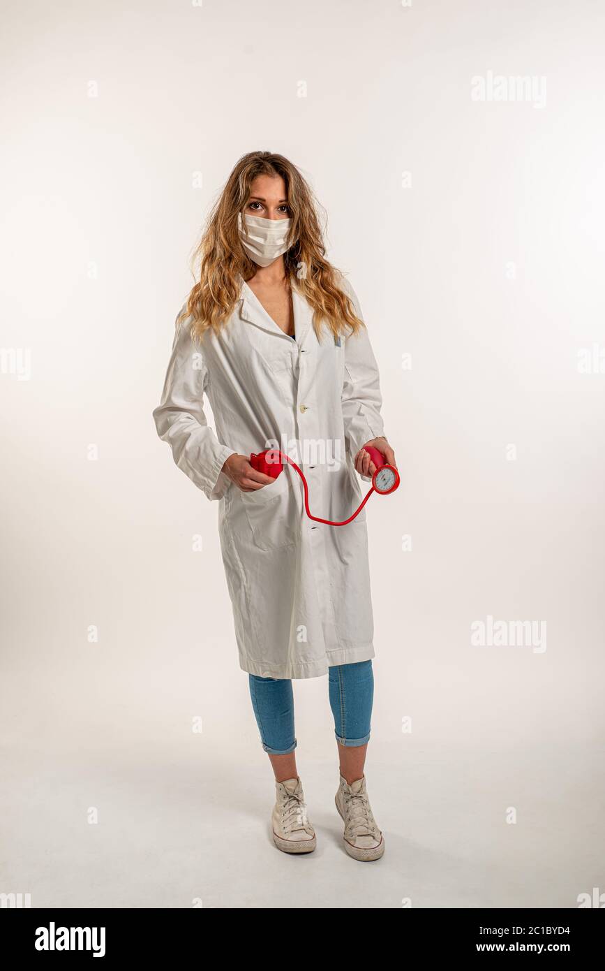 Donna che indossa uniforme medica che tiene uno sfigmomanometro su uno sfondo bianco Foto Stock