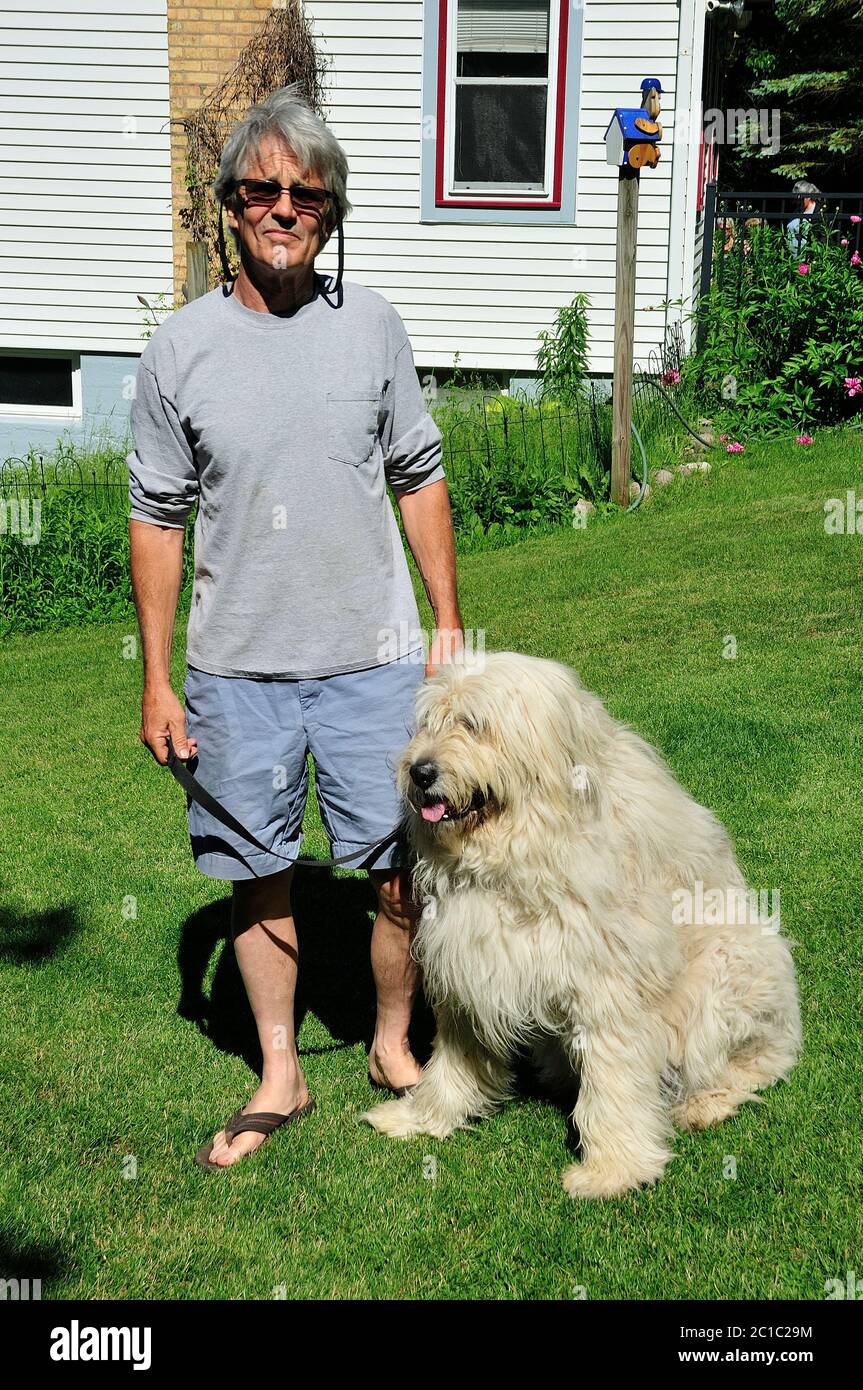 Uomo che posa nel suo cortile con il suo cane Chloe che è parte andaluso Shepard e parte Grande Piranese. Foto Stock