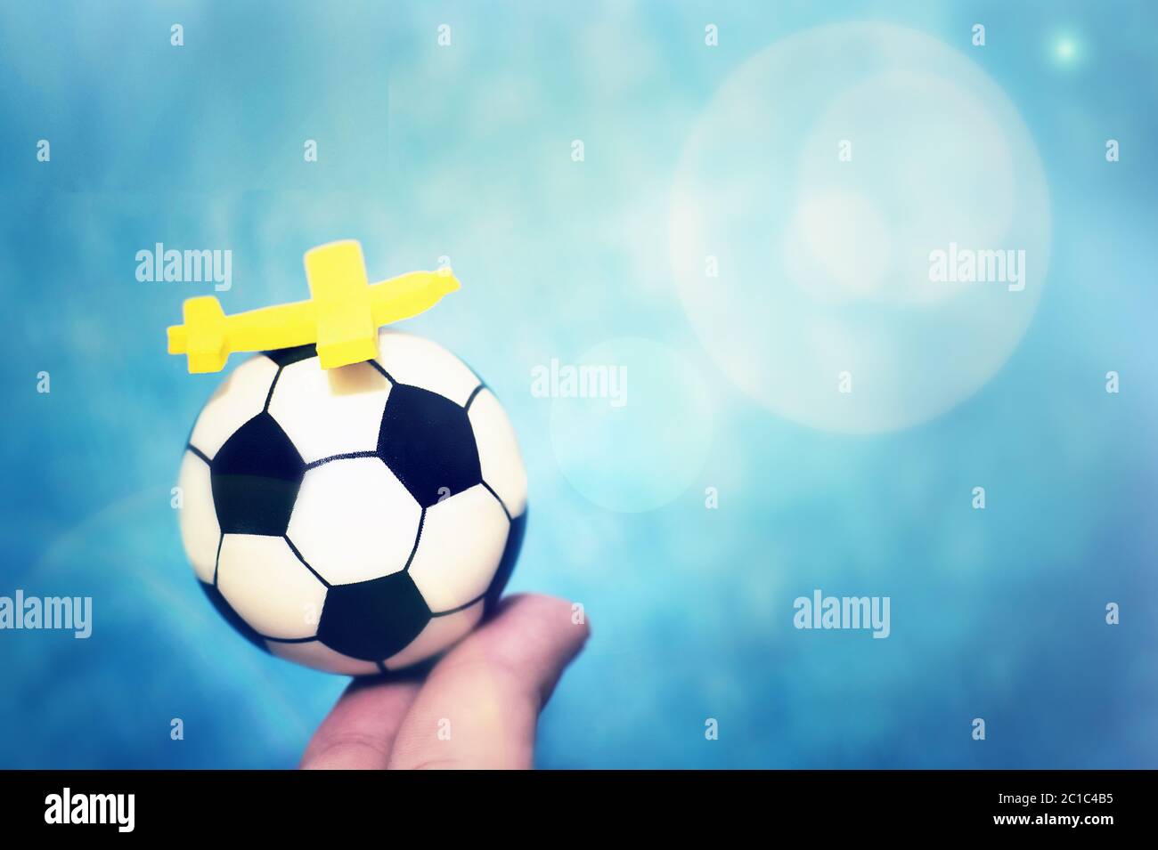 Giallo aeroplano giocattolo su un pallone da calcio. Il concetto di volo per il campionato di calcio. Foto Stock