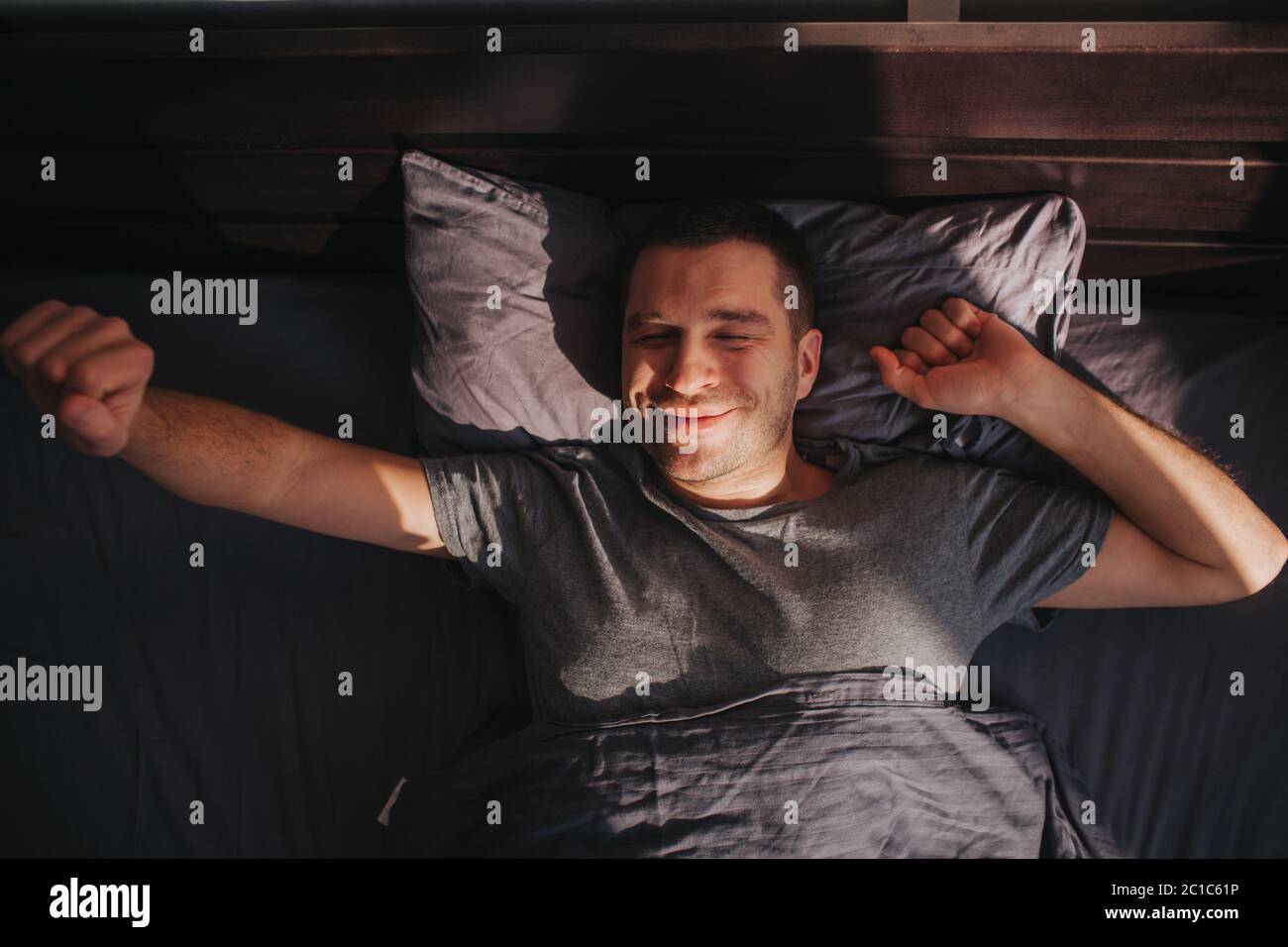 Un uomo nel letto al mattino. Sta allungando. Ottimo inizio di giornata. Foto Stock