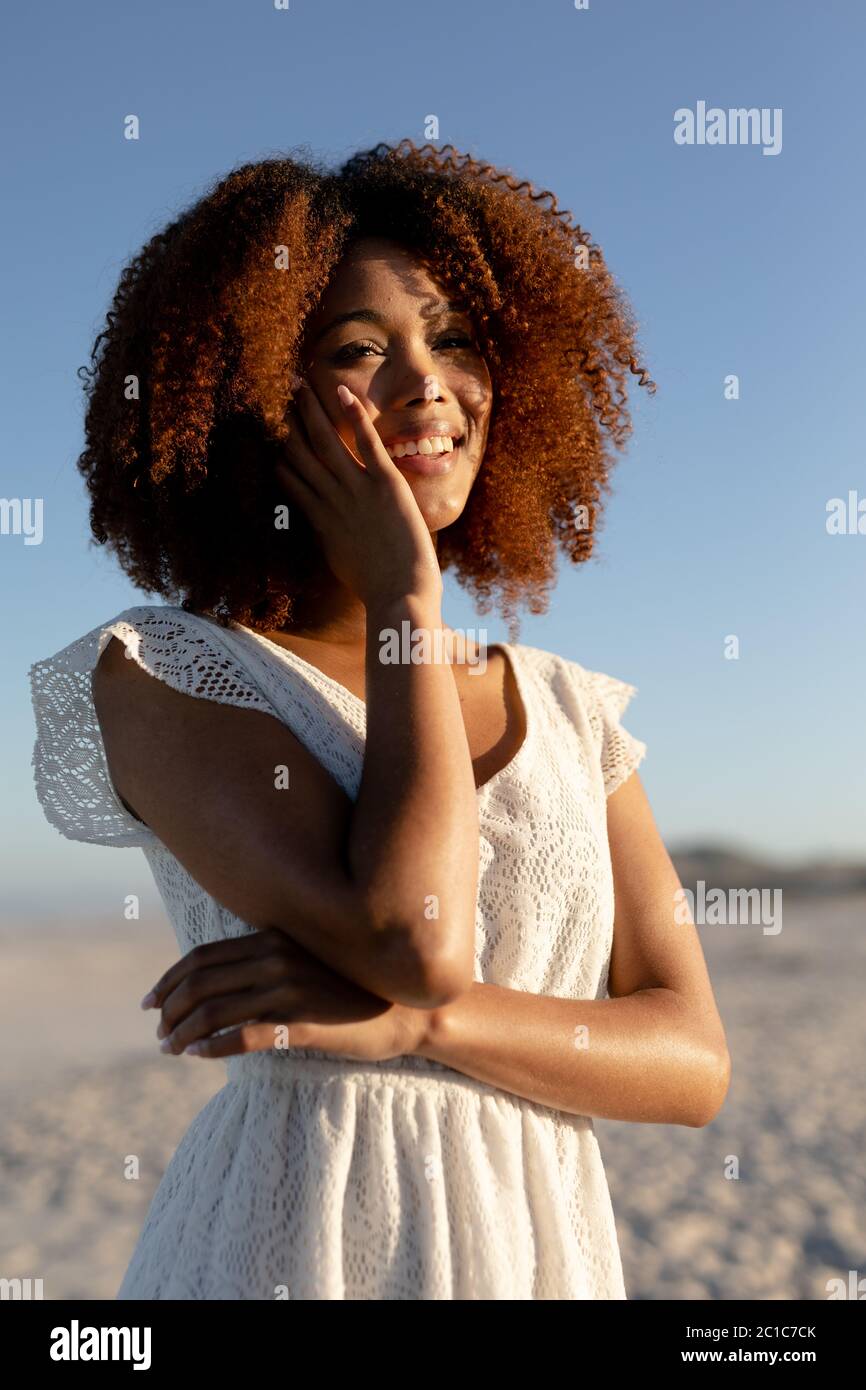 Donna mista con la mano sul viso in spiaggia in una giornata di sole Foto Stock