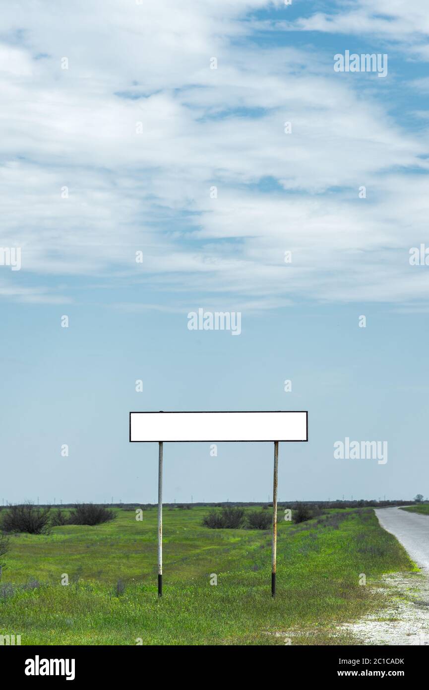 Cartello vuoto per il nome di una città o di un villaggio zona popolata vicino alla strada in campagna contro un cielo blu e WI Foto Stock