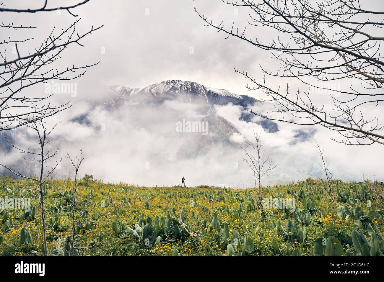 Piccolo turista con zaino verde che guarda la valle di montagna di neve in Almaty in primavera in Kazakistan Foto Stock