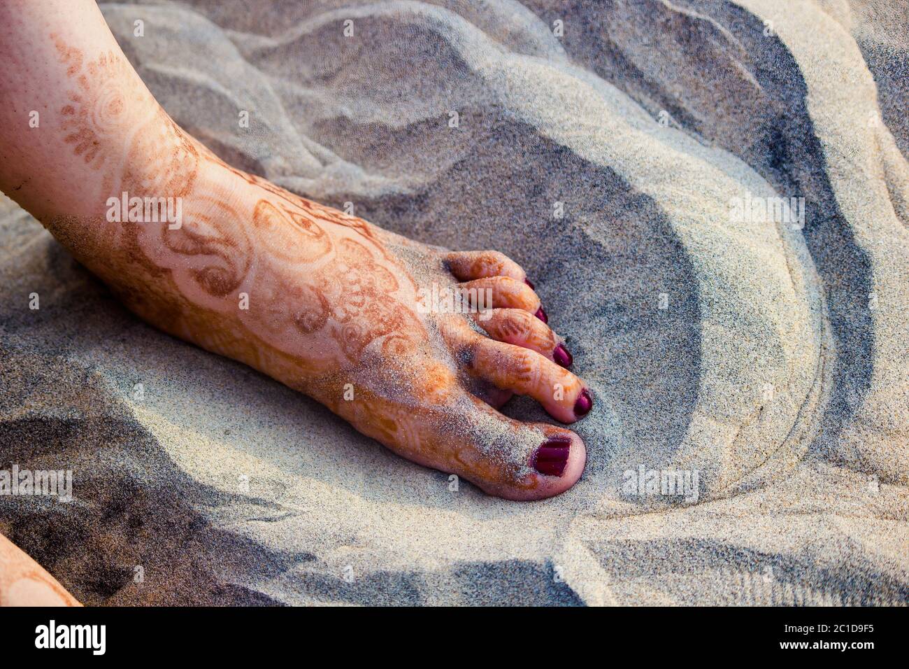 Un piede che mostra l'hennè su una sabbia Foto Stock