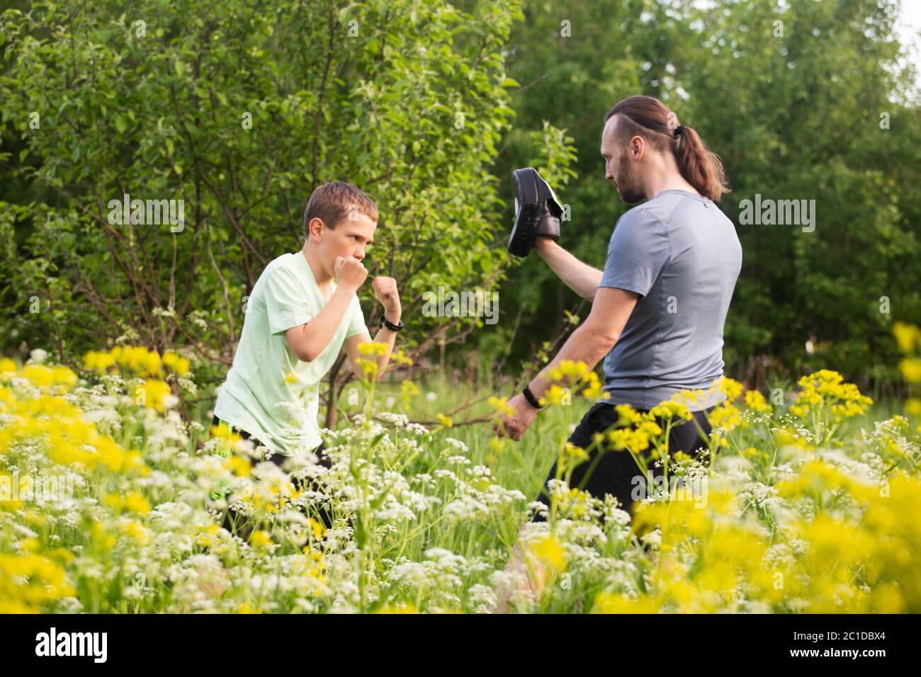 Padre e figlio si allenano a box nel parco all'aperto, combattendo, cura, sport, genitorialità, stile di vita sano Foto Stock