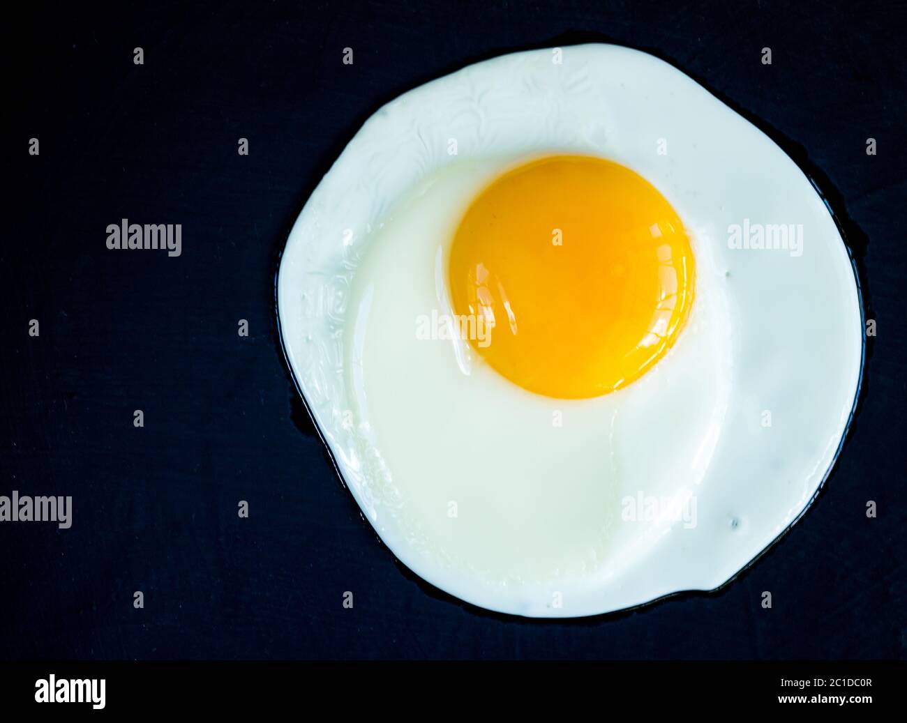Uovo fritto isolati su rustico sfondo nero Foto Stock