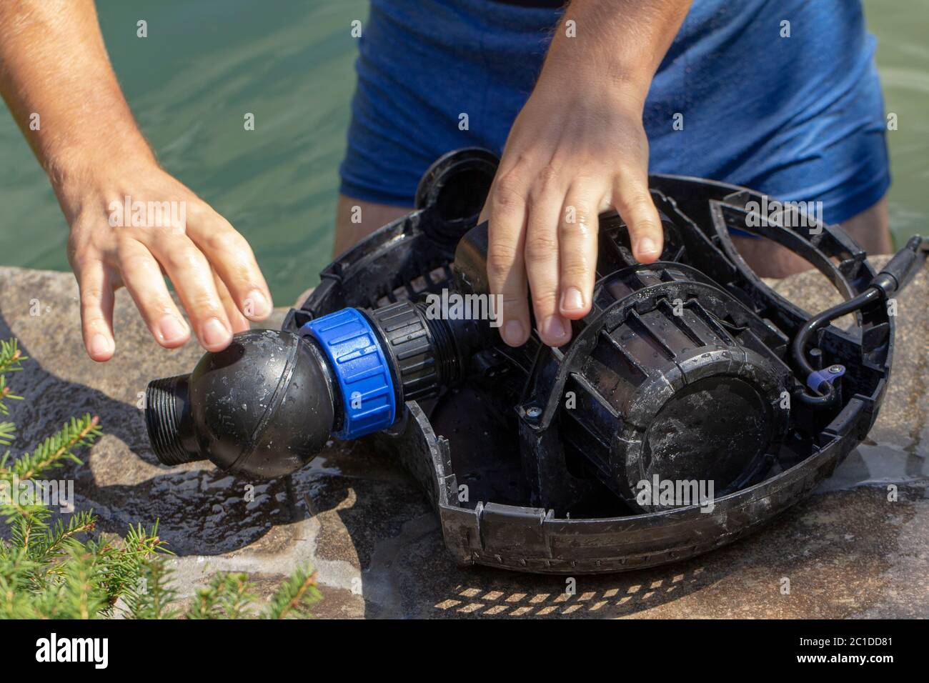 Riparazione della pompa dell'acqua per un piccolo stagno decorativo con una fontana Foto Stock