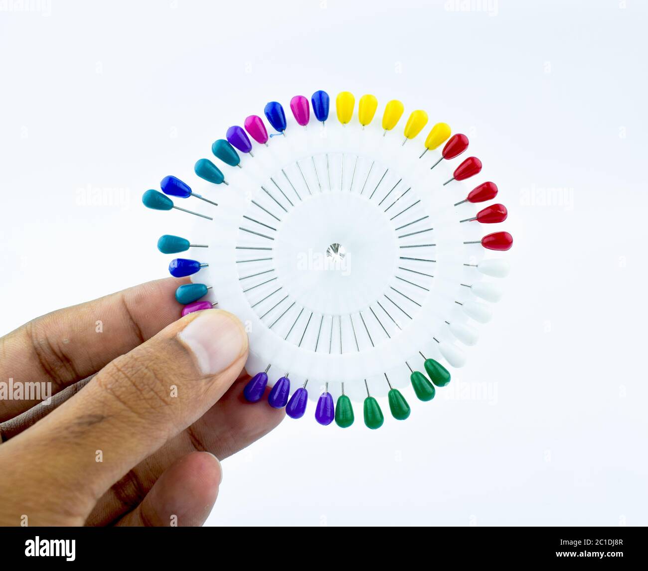 La persona che tiene un mazzo di coloratissime spilla la sua mano con le dita Foto Stock