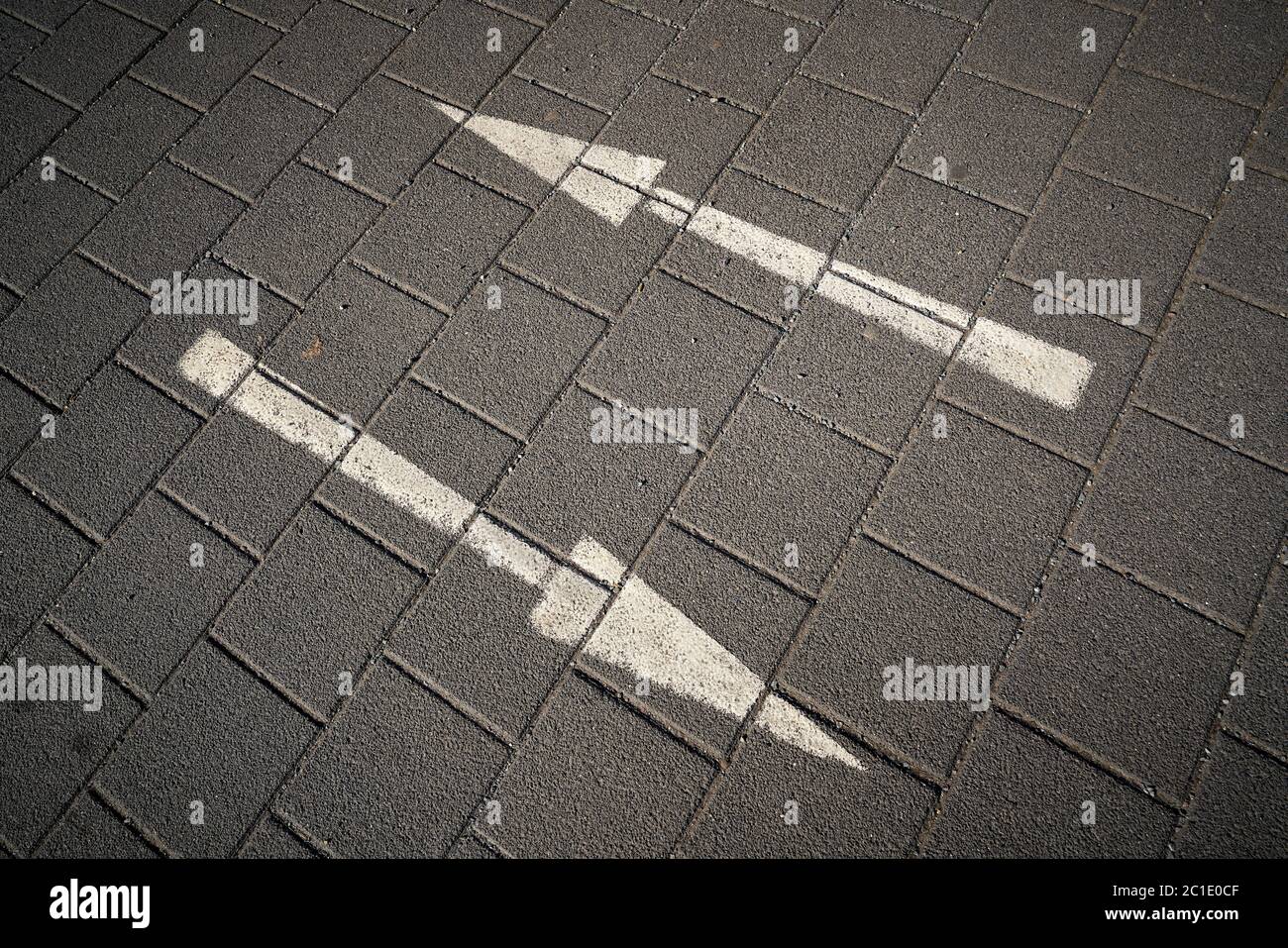 Frecce direzionali su una strada lastricata Foto Stock