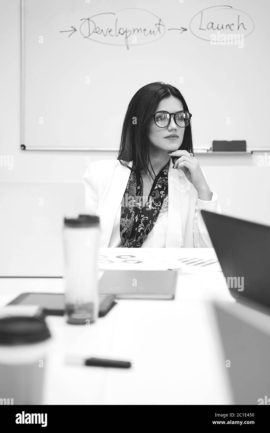 Donna d'affari caucasica sicura e premurosa o manager da solo in un ufficio moderno. Foto Stock